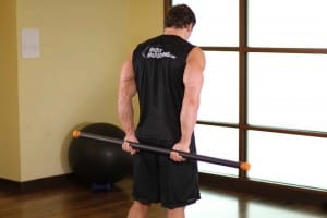 Stretching the rear delts with gymnastic stick