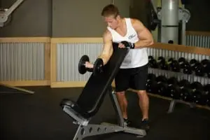 Flexion of hands on a biceps, standing next to the inclined bench