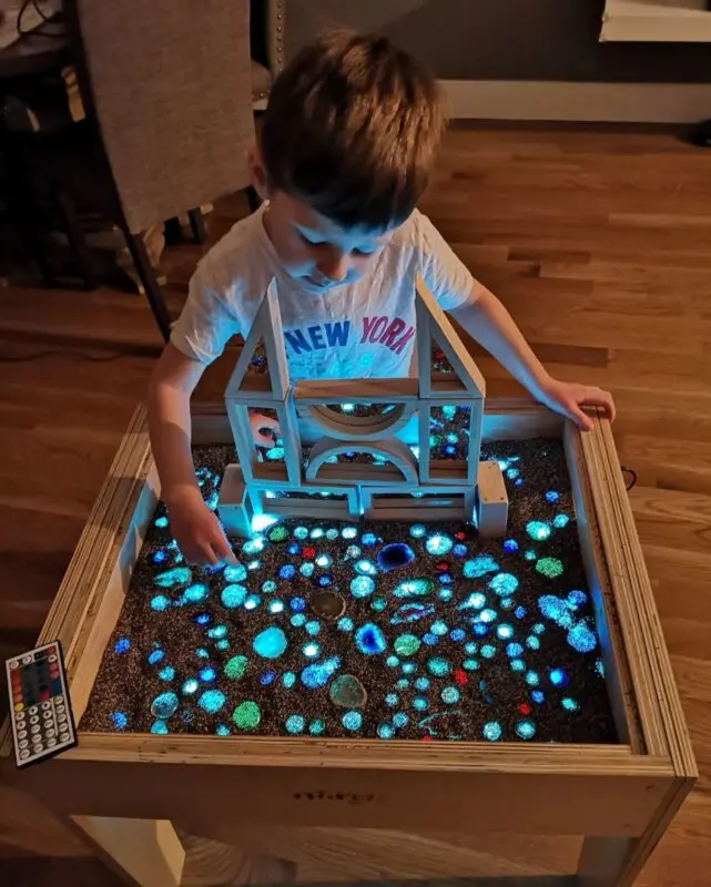 Drawing with sand for children on glass, on a table with colored backlight