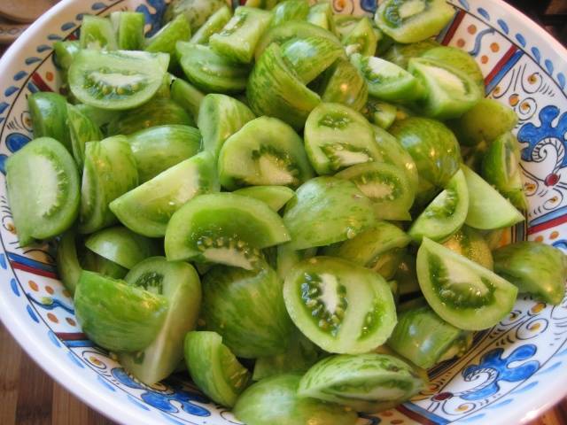 Sliced ​​marinated green tomatoes with hot peppers