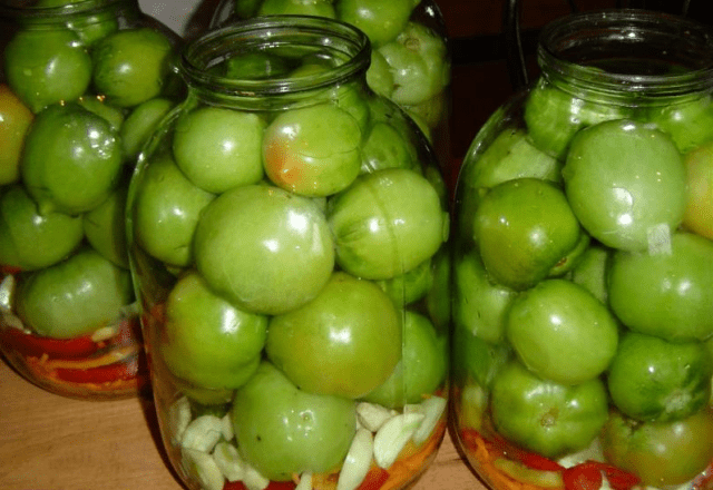 Sliced ​​marinated green tomatoes with hot peppers