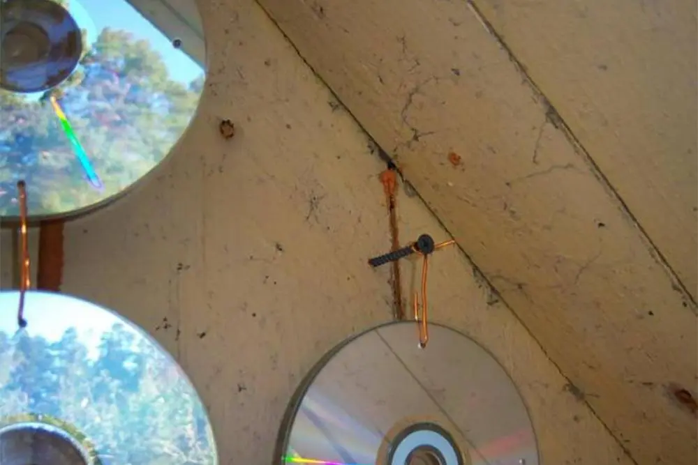 CDs are pierced with a nail and hung on wire or rope.  Source: "100 hares"